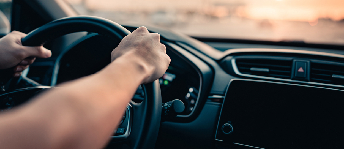 Close-up - Hand of man driving car on the road.