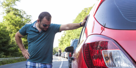 man looking at damage on car