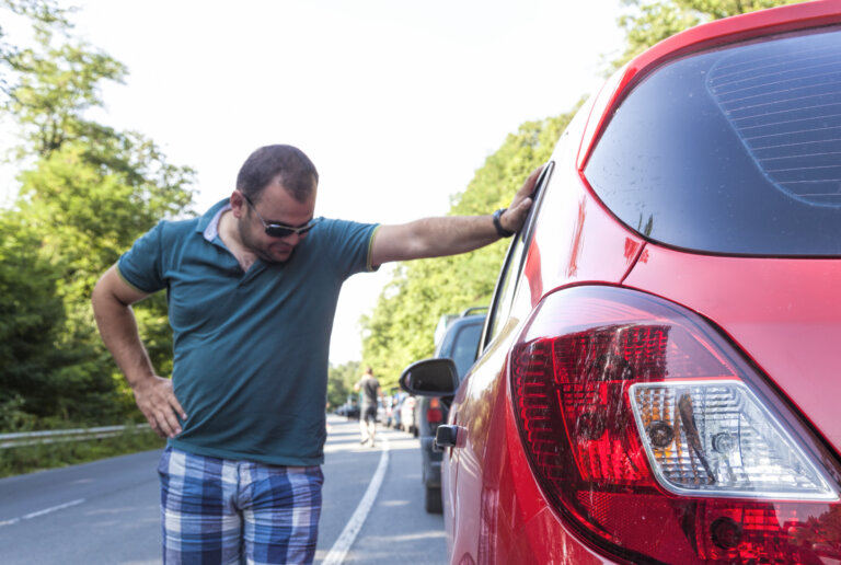 man looking at damage on car