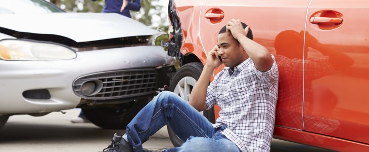 Man at the scene of a car accident calling friend