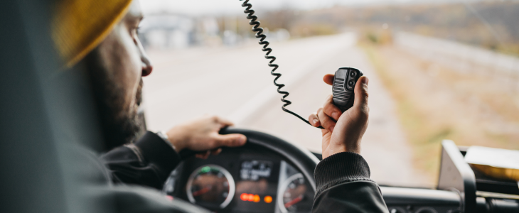 Truck driver driving distracted while holding his walkie talkie