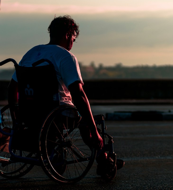 photo of young man in wheelchair with sunset