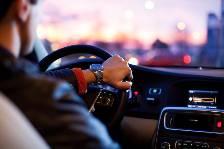 partial view of driver at dusk taken from the backseat of car