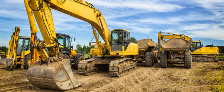 Heavy construction equipment, including excavators and dump trucks, on a worksite in North Dakota, related to personal injury attorney