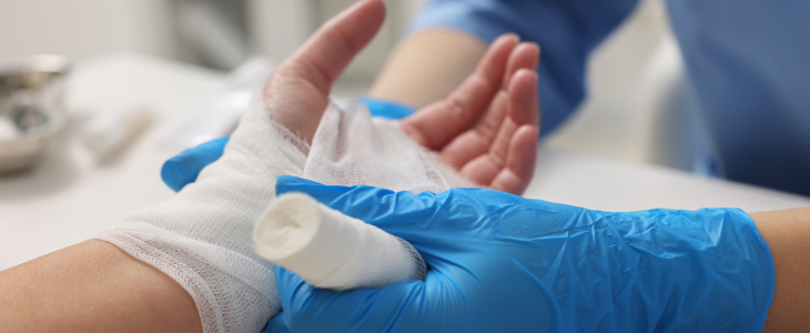 Bandaged hand being treated by a medical professional wearing blue gloves in North Dakota, related to personal injury attorney
