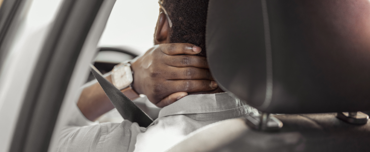 Person in a car holding their neck in apparent pain in North Dakota, related to personal injury attorney