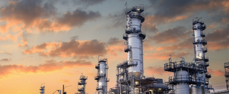 Industrial refinery plant with tall towers and complex piping system at sunset in North Dakota, related to personal injury attorney