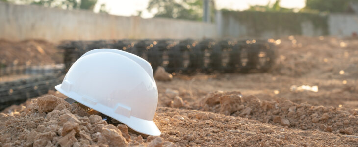 White hardhat on dirt at construction site, highlighting unsafe workplace practice.