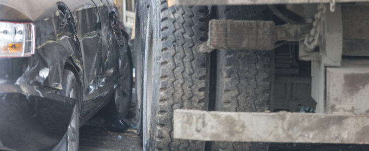 A truck run into the sidewalk and crush the car.