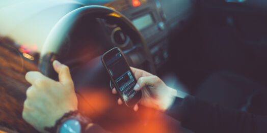 Young businessman driving a car and using smartphone