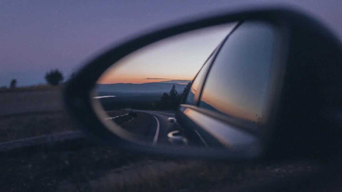 Looking for blind spot in car mirror on a road.