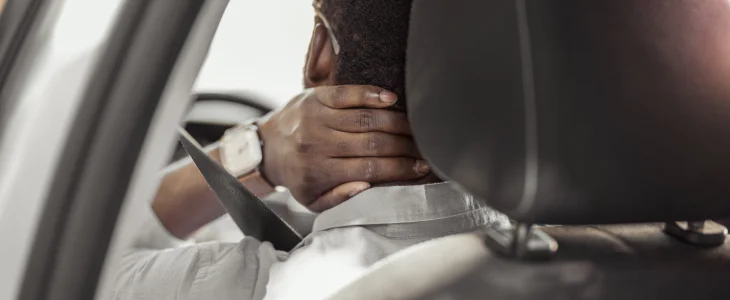 Person in car holds neck in pain in North Dakota, related to personal injury attorney