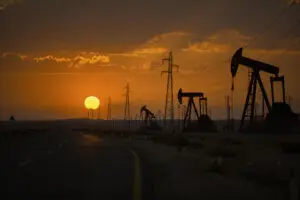 Oil wells and power lines on the side of the highway.