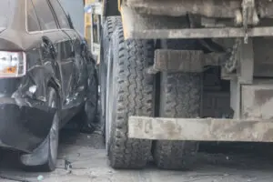 A truck run into the sidewalk and crush the car.